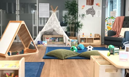The babies room with a soft play mat, timber mirror frame, canopy tent and low shelving.